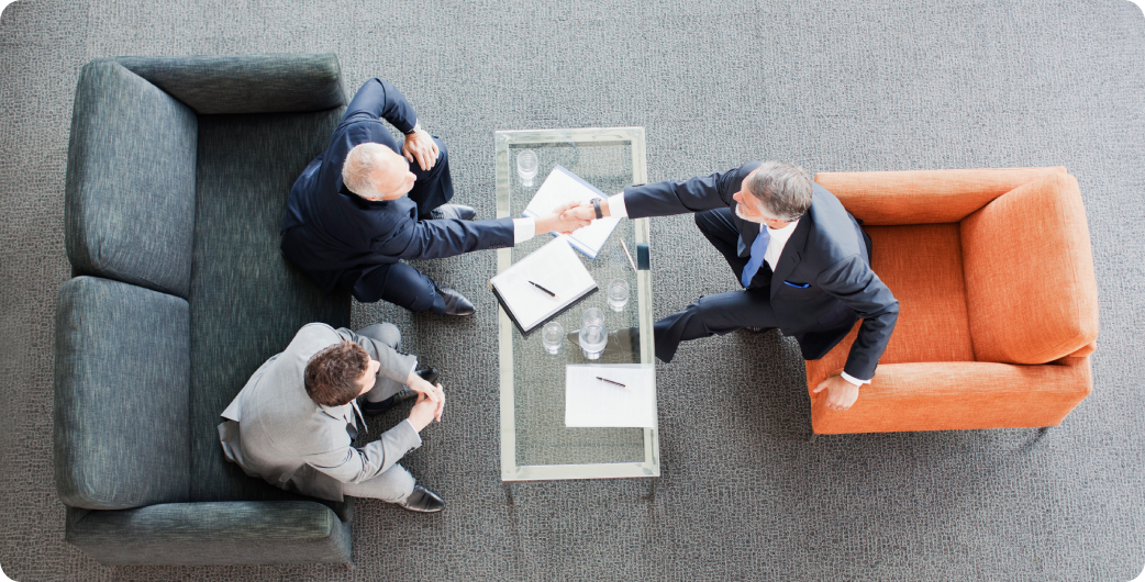 Three businessmen shaking hands in meeting.